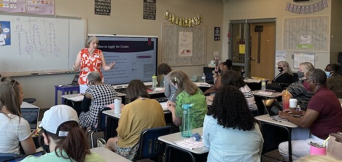 Ann Clemments addresses adults sitting at desks in a classroom